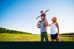 A couple and their child standing in a grass field